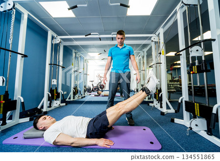 Rehabilitation therapy. Young man doing exercises on mat Rehabilitation therapy. Young man doing exercises on mat 134551865
