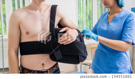 Nurse putting a sling on patients arm that is broken. Injury Nurse putting a sling on patients arm that is broken. Injury 134551891
