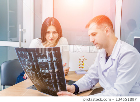 Traumatologist showing MRI film to patient in hospital. Traumatologist showing MRI film to patient in hospital. 134551897