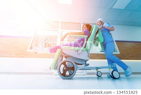 Nurse moves mobile medical chair with patient at hospital. Medical equipment. Nurse moves mobile medical chair with patient at hospital. Medical equipment. 134551925