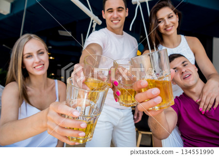 Cheerful friends in the pub. Drinking beer, talking, having fun. 134551990