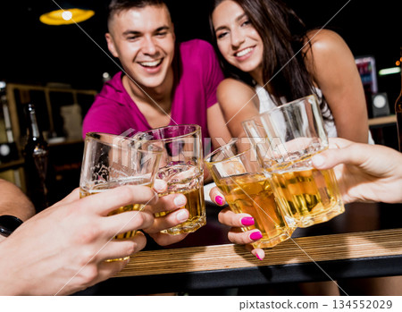 Cheerful friends in the pub. Drinking beer, talking, having fun. 134552029