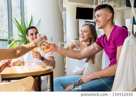 Cheerful friends in the pub. Drinking beer, talking, having fun. 134552030