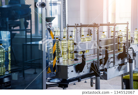 Bottling line of sunflower oil in bottles. Vegetable oil production plant. Bottling line of sunflower oil in bottles. Vegetable oil production plant. 134552067