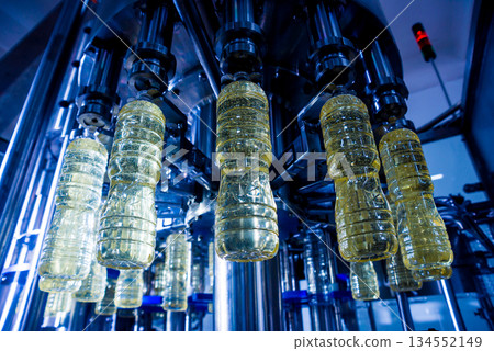 Bottling line of sunflower oil in bottles. Vegetable oil production plant Bottling line of sunflower oil in bottles. Vegetable oil production plant 134552149