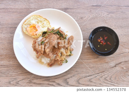 spicy fried slice fermenting soft pork with basil topping egg on rice in plate dipping chili fish sauce 134552378