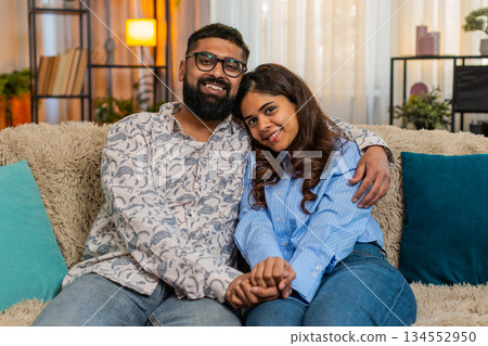 Indian family couple man woman holding hands sit in silence at home, sharing peaceful emotional bond Indian family couple man woman holding hands sit in silence at home, sharing peaceful emotional bond 134552950