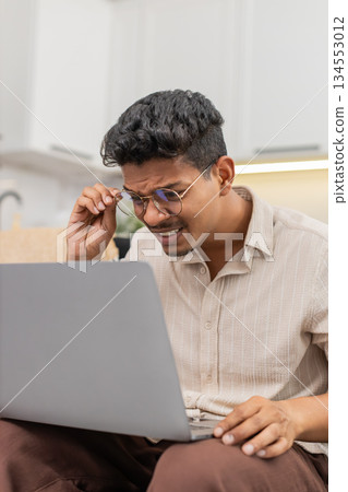 Indian man puts on glasses for clear reading of small notebook text vision focus resumes daily work Indian man puts on glasses for clear reading of small notebook text vision focus resumes daily work 134553012