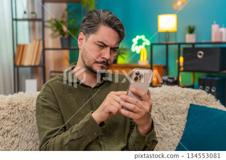 Middle-aged man slowly editing smartphone text deletes rewrites hesitates deciding what to message 134553081