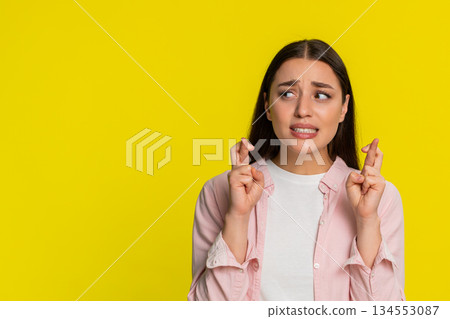 Woman crossing fingers closing eyes hoping for luck positive emotion wishful thoughtful expression Woman crossing fingers closing eyes hoping for luck positive emotion wishful thoughtful expression 134553087