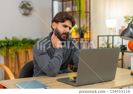 Indian man stops work due to neck pain massages neck unhappy face closes laptop for short break sore Indian man stops work due to neck pain massages neck unhappy face closes laptop for short break sore 134553119