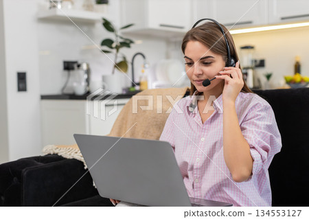 Young woman with headset starts laptop video call with client greets listens asks helpful questions 134553127