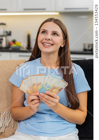 Young woman counts euro cash money plans big new purchase feels proud of savings salary and bonus Young woman counts euro cash money plans big new purchase feels proud of savings salary and bonus 134553429