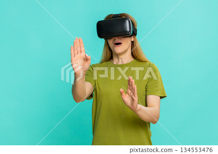 Woman wearing VR headset looking around exploring virtual reality experience with curious emotion 134553476