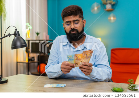 Indian man counts euro money cash banknotes feels wealthy salary profit extra winnings game jackpot Indian man counts euro money cash banknotes feels wealthy salary profit extra winnings game jackpot 134553561