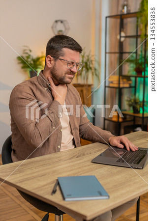 Sick man freelancer feeling unwell suffering from sore throat touches chest while coughing at home 134553838