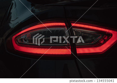 Automotive detail: the illuminated rear light of a parked car in the dark Automotive detail: the illuminated rear light of a parked car in the dark 134555041
