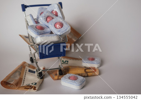 Dishwasher pods and euro banknotes in a shopping trolley, symbolizing high household cost 134555042