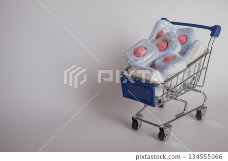 Organized laundry: stack of bright dishwasher tablets in a wire shopping trolley 134555066
