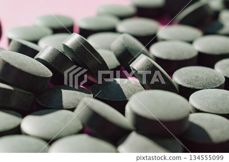 Algae superfood: green Spirulina tablets isolated on a vibrant pink background 134555099