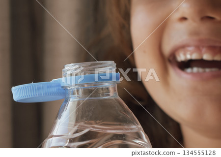 Happy child and water bottle: symbolising health, well-being, and the need for hydration Happy child and water bottle: symbolising health, well-being, and the need for hydration 134555128