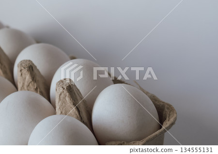 White chicken egg in a carton, symbolizing the rising cost of groceries and food prices White chicken egg in a carton, symbolizing the rising cost of groceries and food prices 134555131