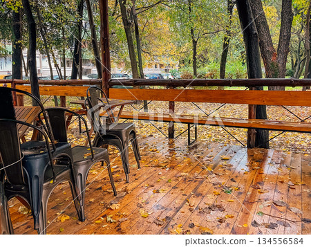 rainy city patio, overcast sky above wet wooden balcony with abandoned seating and puddles reflecting trees rainy city patio, overcast sky above wet wooden balcony with abandoned seating and puddles reflecting trees 134556584
