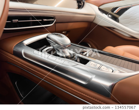 Automatic gear stick of a modern car. Modern car interior details. Close up view. Car inside. Automatic transmission lever shift. Brown leather interior with stitching 134557067