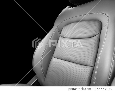Modern luxury car black leather interior. Part of black leather car seat details with white stitching. Interior of prestige car. Perforated leather seats isolated on black. Perforated leather. 134557079