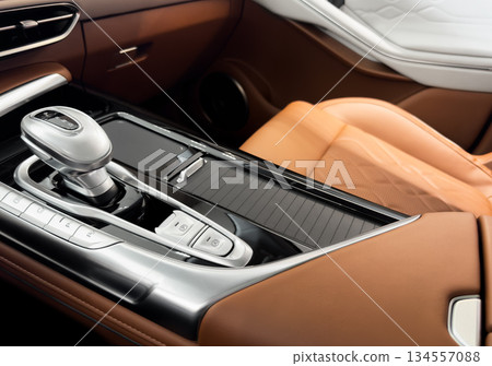 Automatic gear stick of a modern car. Modern car interior details. Close up view. Car inside. Automatic transmission lever shift. Brown leather interior with stitching 134557088