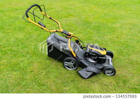 Mowing lawns. Lawn mower on green grass. Mower grass equipment. Mowing gardener care work tool close up view. Soft lighting Mowing lawns. Lawn mower on green grass. Mower grass equipment. Mowing gardener care work tool close up view. Soft lighting 134557093