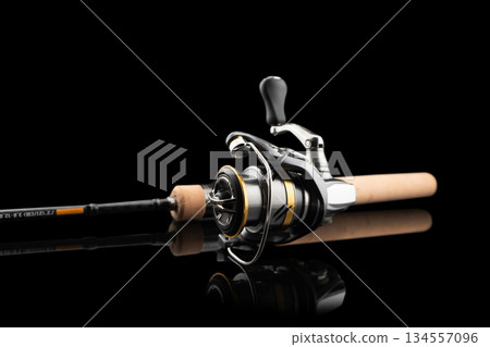 Fishing rod spinning with the line close-up. Fishing rod and reel isolated on black background. Fishing rod rings. Tackle. Fishing spinning reel. Fishing rod spinning with the line close-up. Fishing rod and reel isolated on black background. Fishing rod rings. Tackle. Fishing spinning reel. 134557096