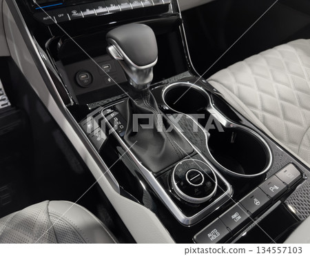 Automatic gear stick of a modern car. Modern car interior details. Close up view. Car inside. Automatic transmission lever shift. White leather interior with stitching 134557103