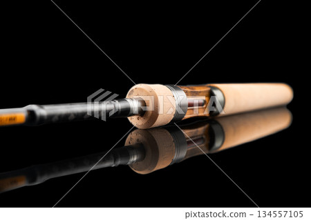 Fishing rod spinning with the line close-up. Fishing rod isolated on black background. Fishing rod rings. Tackle. Fishing spinning reel. Fishing rod spinning with the line close-up. Fishing rod isolated on black background. Fishing rod rings. Tackle. Fishing spinning reel. 134557105