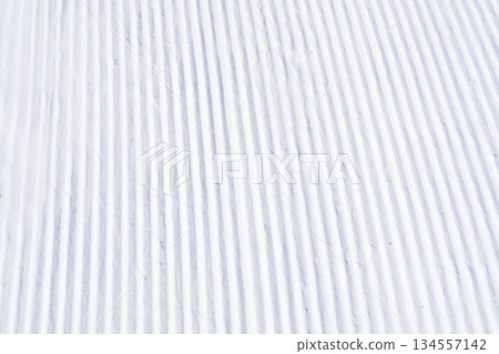 Close up of groomed tracks on a slope in a downhill ski resort. Close-up straight line rows of freshly prepared groomed ski slope Close up of groomed tracks on a slope in a downhill ski resort. Close-up straight line rows of freshly prepared groomed ski slope 134557142