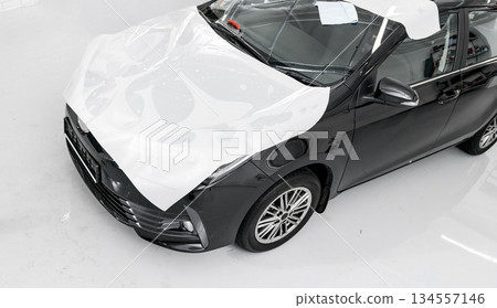 Car wrapping specialist putting vinyl foil or film on car. Protective film on the car. Applying a protective film to the car with tools for work. Car detailing. Car paint protection 134557146