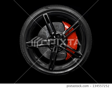 Car alloy wheel and tyre isolated on black background. New alloy wheel with tire and red carbon ceramic brakes. Alloy rim isolated. Car wheel disc. Car spare parts Car alloy wheel and tyre isolated on black background. New alloy wheel with tire and red carbon ceramic brakes. Alloy rim isolated. Car wheel disc. Car spare parts 134557252