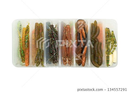 Jig silicone fishing lures in plastic tackle lure box. Silicone fishing baits isolated. Colorful baits. Fishing spinning bait. Silicone soft plastic bait lure 134557291