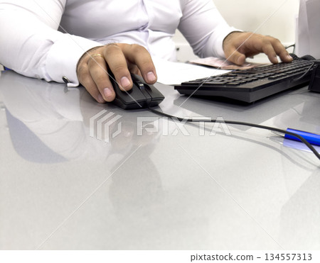 Hands of businessman holding computer mouse and keyboard in office. Male office worker focused on a computer work. Hand on computer mouse close up 134557313