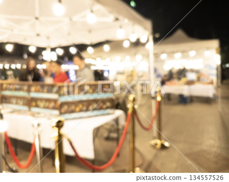 Blurry market fair environment around shopping community and market place at night. Blurred fair background texture with bokeh lights 134557526