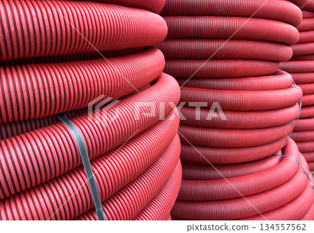 HDPE corrugated pipe texture background. Protection underground cable. Rolled up red corrugated PVC pipe. Red building pipes. Coated corrugated construction pipe. HDPE corrugated pipe texture background. Protection underground cable. Rolled up red corrugated PVC pipe. Red building pipes. Coated corrugated construction pipe. 134557562