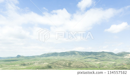Scenic aerial mountain view to green forest valley in sunlight among mountain ranges and hills on horizon. Green landscape with sunlight mountains. 134557582