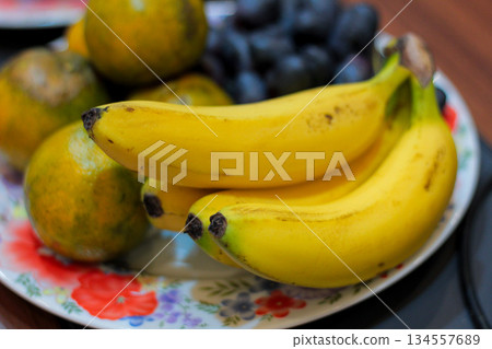 Fresh Bananas Oranges Grapes on Floral Plate 134557689