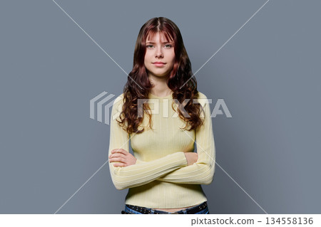 Portrait of serious confident teenage girl with crossed arms on gray background 134558136