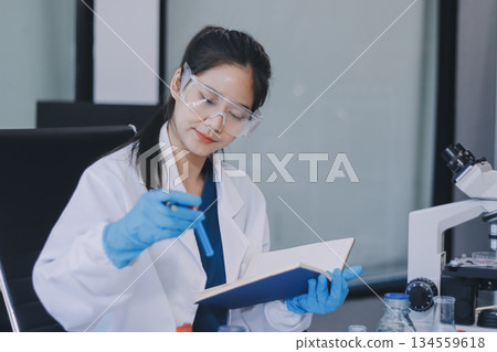 Portrait, science and happy woman on laptop in lab to research chemistry, test or innovation. Microscope, scientist and face of medical doctor in goggles for microbiology, healthcare or pharma study 134559618