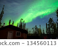 A fantastic night view of the aurora spreading over the forest and lodge in Yellowknife, Canada 134560113