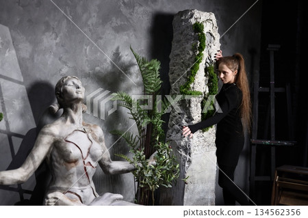 Woman interacts with luminous globe amid ancient statue setting 134562356