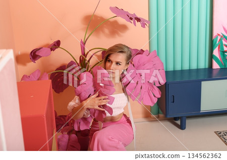 Woman showcases colorful plant arrangement near furniture Woman showcases colorful plant arrangement near furniture 134562362