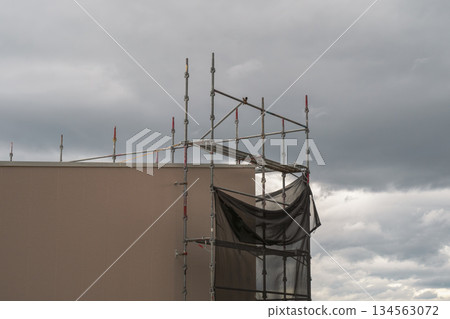 A construction site where protective sheets were torn off by a sudden gust of wind 134563072