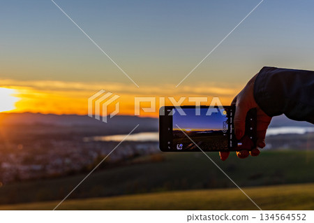 Taking a photo of a golden sunset over the lake with a smartphone Taking a photo of a golden sunset over the lake with a smartphone 134564552